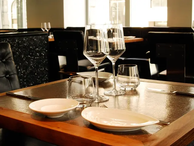 Image looks like it is clicked inside a restaurant. There is a table on which glasses and plates...